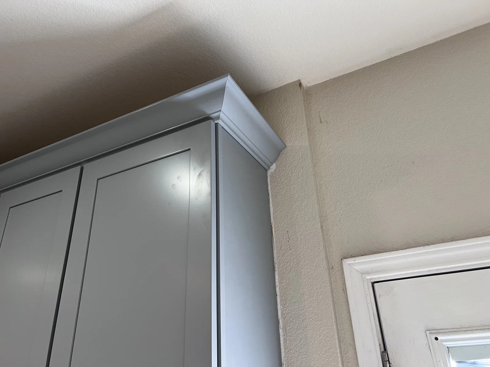 Close view of pale upper cabinetry and crown trim