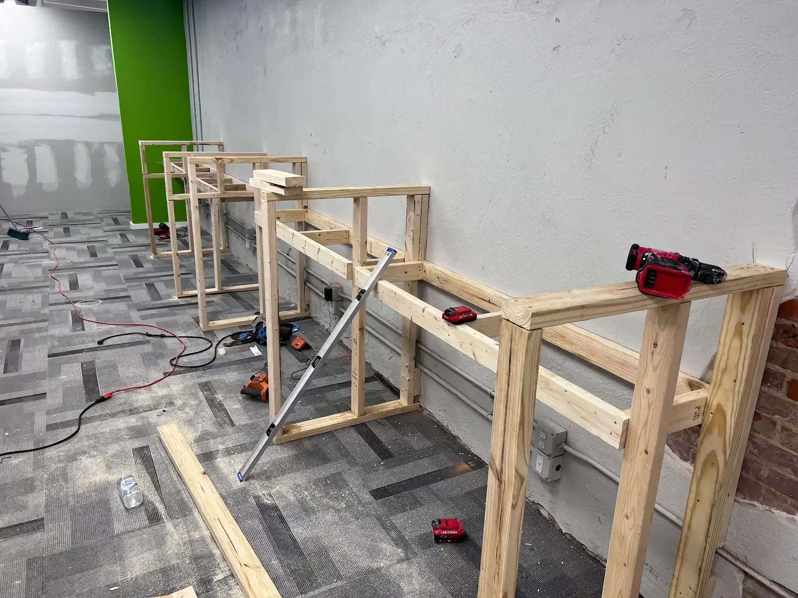 A row of timber frames against a wall with tools and a level nearby