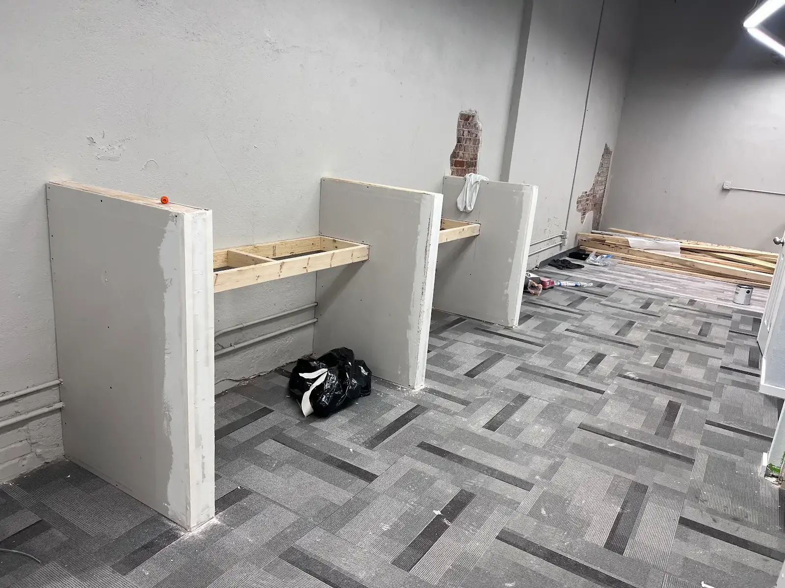 White paneled partitions joined by timber rails over patterned grey flooring
